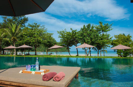 PP Charlie Beach Resort, Phi Phi Island. Beachfront pool view with lounge chairs, drinks, and towels. Small gay hotel in Thailand.