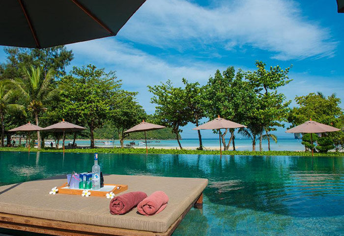 PP Charlie Beach Resort, Phi Phi Island. Beachfront pool view with lounge chairs, drinks, and towels. Small gay hotel in Thailand.