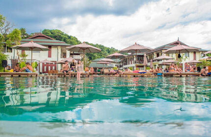 PP Princess Resort pool scene. Gay popular hotel in Koh Phi Phi. Guests relax on loungers by the pool under umbrellas. Tropical getaway.