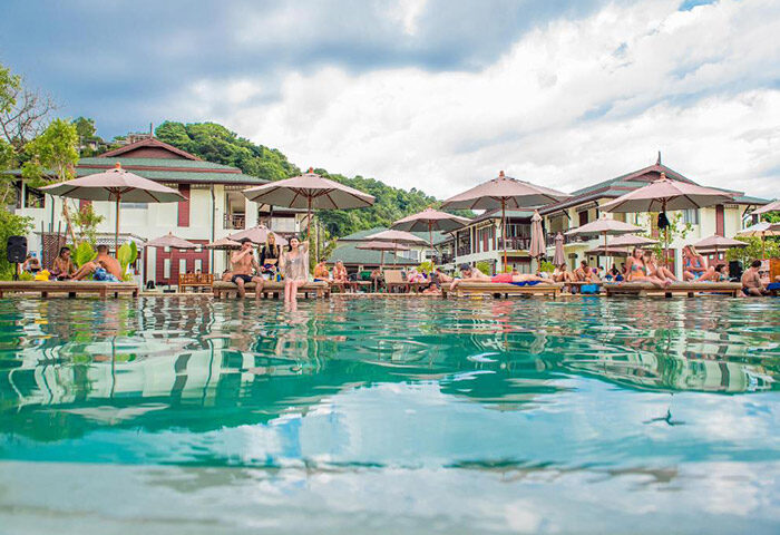 PP Princess Resort pool scene. Gay popular hotel in Koh Phi Phi. Guests relax on loungers by the pool under umbrellas. Tropical getaway.