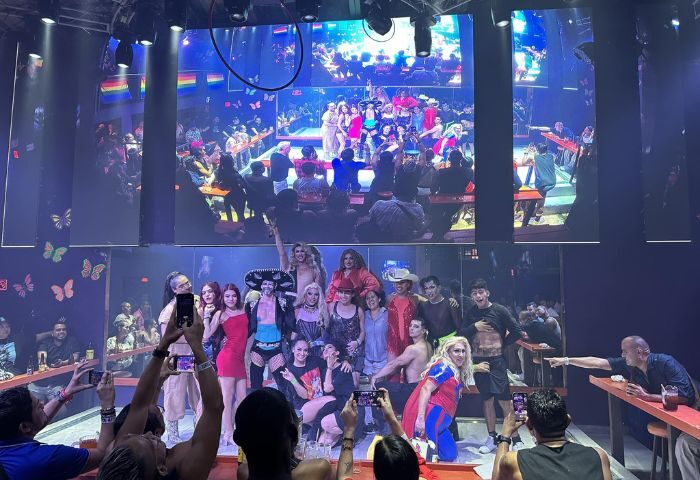 Paco's Ranch gay bar in Puerto Vallarta: Drag queens pose for photos in front of a crowd. Gay nightlife scene, popular gay travel destination.
