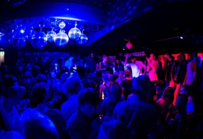 Palms on Oxford Sydney: Gay bar disco with a crowd of people dancing under disco balls and blue and pink lights. Gay nightlife travel.