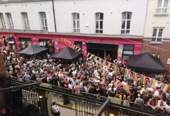 Crowd outside Pantibar, a popular gay bar in Dublin. Rainbow flags decorate the venue, celebrating LGBTQ+ pride. Gay travel destination.