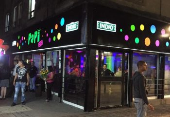 Papi Fun Bar gay party in Mexico. The bar's exterior at night with colorful lights and people outside. Gay travel advice.