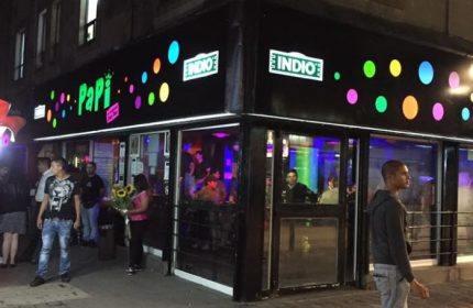 Papi Fun Bar gay party in Mexico. The bar's exterior at night with colorful lights and people outside. Gay travel advice.