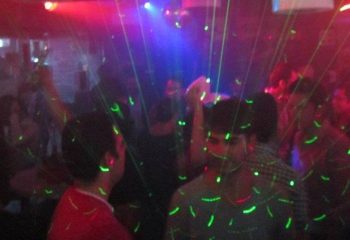 Gay party at Papi Fun Bar in Mexico. Crowd of men dancing under laser lights. Nightlife scene, travel destination.