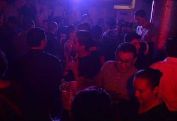 Crowded Papi Fun Bar gay party in Mexico. People socializing under blue and red lights. Gay travel advice, nightlife scene.