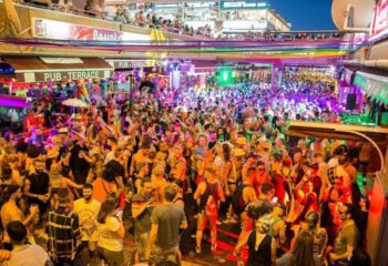 Gay nightlife at Parrots Pub, a popular gay bar in Yumbo Centre, Maspalomas, Gran Canaria. Crowded scene, rainbow decorations.