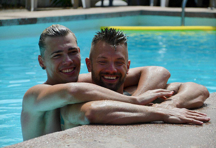 Gay couple at Paso Chico Gay Hotel, most booked hotel among gay men. Two men in a pool smiling, enjoying their vacation.