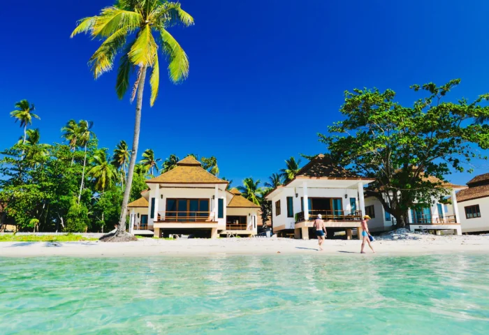 Pawapi Koh Mook Resort in Trang: Beachfront bungalows with gay couple walking along the shore. Tropical paradise for gay travelers.