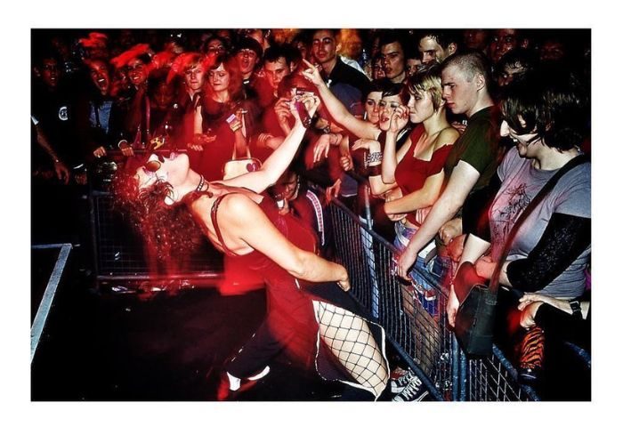 Peaches in Toronto performing for a crowd of fans. Gay men travel to Toronto to see live music. Red lighting, fishnets, and sunglasses.