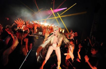 Peaches performing in Toronto. Gay travel scene with a crowd enjoying the show. Stage lights and performers in costumes. Toronto nightlife.
