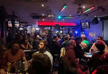 Pegasus on Church gay bar in Toronto. A lively, crowded scene of gay men enjoying drinks and socializing in a dimly lit space.