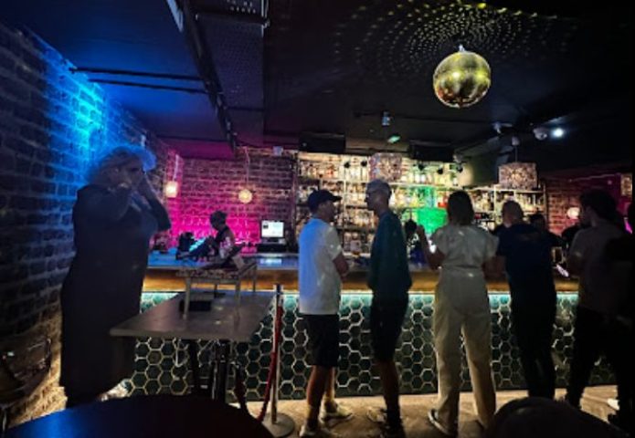 Inside Penny Lane Gay Bar Dublin: People at the bar, disco ball, DJ, and colorful lighting. Gay travel advice.