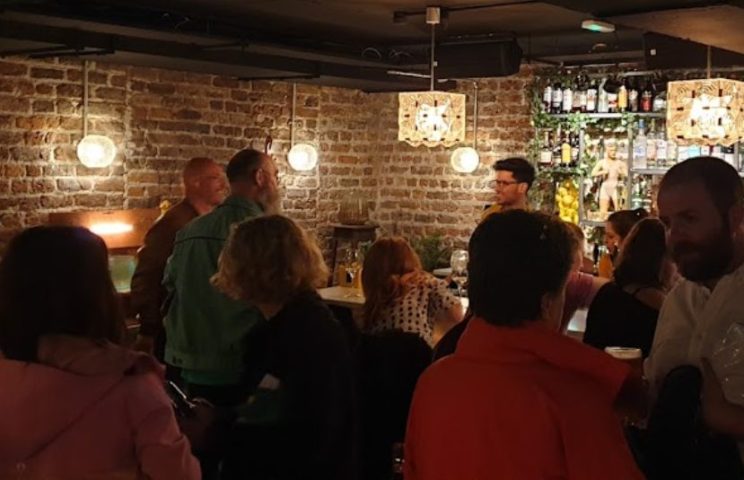 Inside Penny Lane Gay Bar Dublin. Brick walls, warm lighting, people socializing. Dublin's gay scene offers a welcoming spot for travelers.