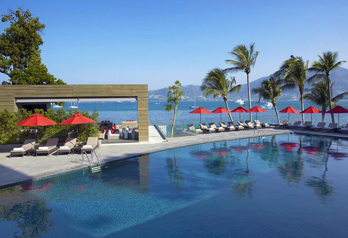 Amari Phuket beachfront gay hotel pool view. Thailand resort with palm trees, red umbrellas, and ocean view. Perfect for big group of friends.