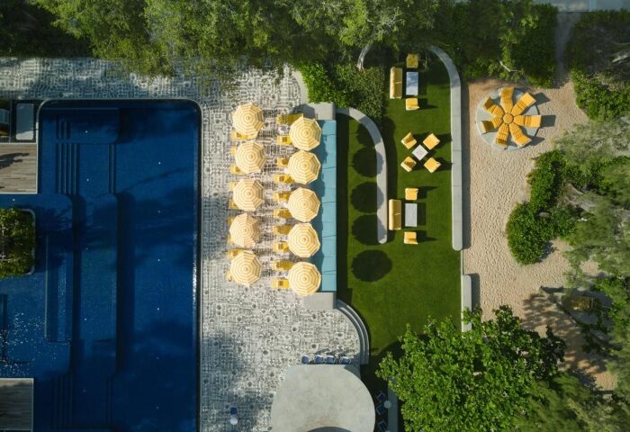 Aerial view of The Standard, Hua Hin, a perfect city break gay beach hotel. Pool, yellow umbrellas, and lounge areas offer a stylish retreat.