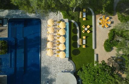 Aerial view of The Standard, Hua Hin, a perfect city break gay beach hotel. Pool, yellow umbrellas, and lounge areas offer a stylish retreat.