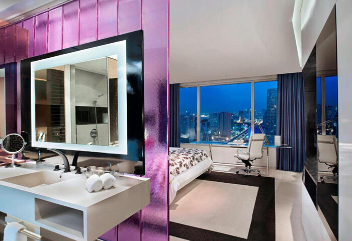 W Bangkok hotel room interior, perfect for a gay honeymoon in Silom gayborhood. Modern design with city view, sink, and mirror.