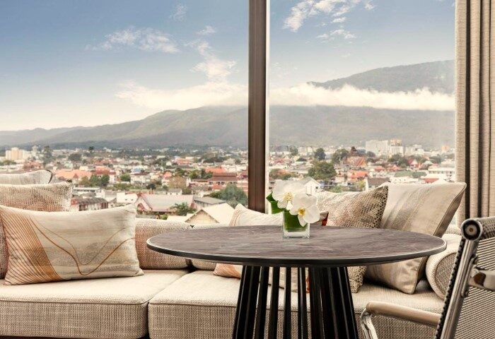 Chiang Mai Marriott Hotel: Honeymoon suite view. Table with orchids, sofa, city and mountains. Perfect gay travel hotels for couples.