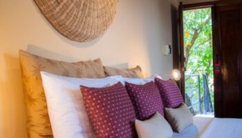 Rambutan Resort Siem Reap bedroom. Gay honeymoon hotels near gay bars in Siem Reap. Cozy bed with decorative pillows and open door to nature.