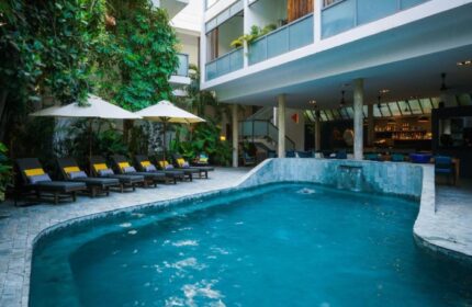 Rambutan Resort Phnom Penh pool view. Perfect gay honeymoon hotels in Phnom Penh. Loungers, umbrellas, and lush greenery surround the pool.