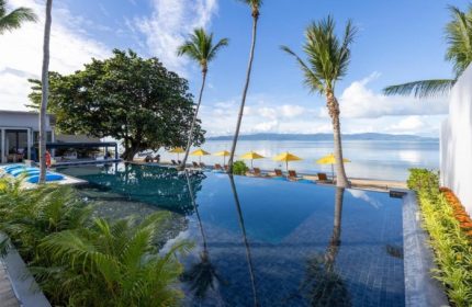 Koh Phangan's beachfront adults-only resort pool. Gay travel goals: palm trees, yellow umbrellas, and ocean views at Explorar Resort.