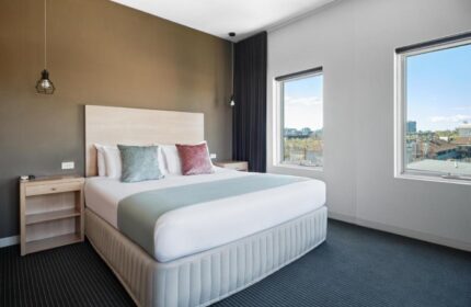 Saint Kilda Beach Hotel room, perfect for a gay honeymoon in Melbourne. Queen bed, bedside tables, and windows with city views. Modern, comfortable.