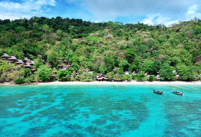 Phi Phi Relax Beach Resort beachfront view. Gay-popular hotel with bungalows, turquoise sea, and lush greenery in Phi Phi, Thailand.