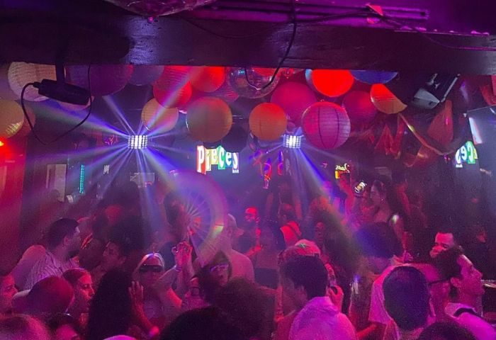 Crowded Pieces Bar in New York City. Gay men enjoy the nightlife with colorful lights, lanterns, and disco balls. Nightlife travel advice.