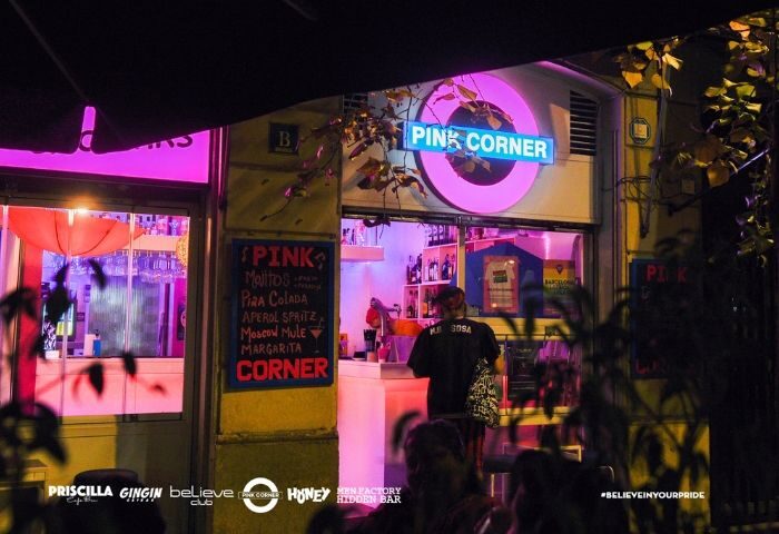 Pink Corner gay bar in Barcelona. Night view of the bar's entrance with pink neon lights and cocktail menu. Gay travel advice.