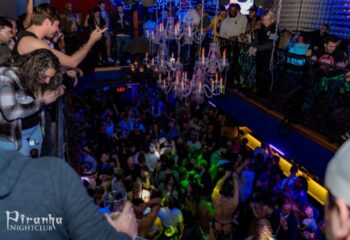 Crowded dance floor at Piranha Nightclub in Las Vegas, a popular gay bar. Chandeliers hang above the revelers. Balcony view.