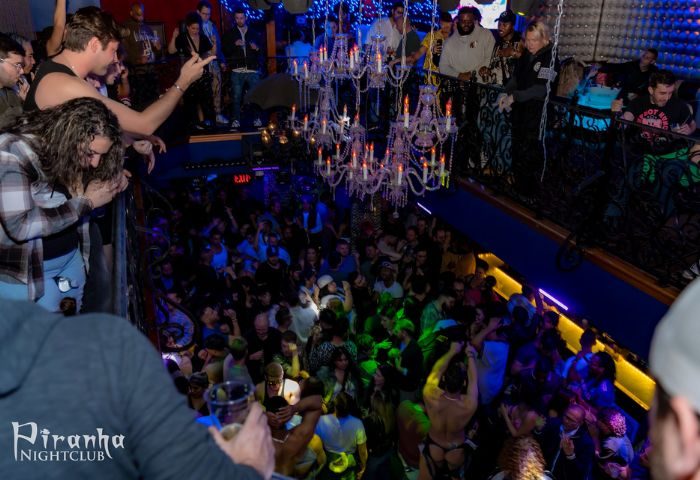 Crowded dance floor at Piranha Nightclub in Las Vegas, a popular gay bar. Chandeliers hang above the revelers. Balcony view.