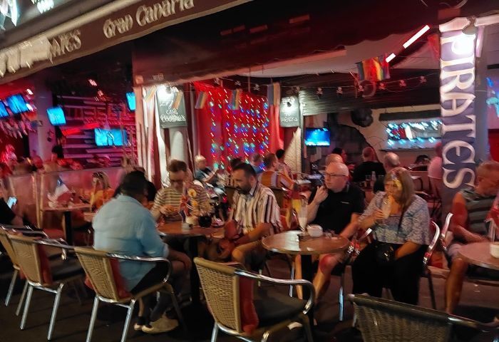 Pirates Bar, Gran Canaria. Gay bar scene with patrons seated at tables, enjoying drinks. Nightlife in Gran Canaria.