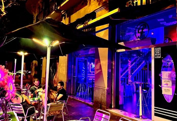 Plata Cocktail Bar, a gay bar in Barcelona. People enjoy drinks outside this vibrant, neon-lit bar, a hot spot for gay men.