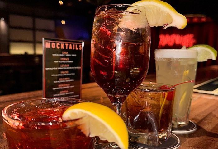 Playhouse Gay Bar in New York: Assorted cocktails, including mocktails, garnished with lemon and cherry. A vibrant nightlife scene.