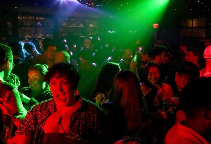 Packed Playhouse gay bar in New York. People dancing under disco ball and colorful lights. Gay nightlife and travel advice.