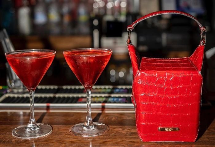 Cocktails & purse at Playhouse gay bar in New York. Red drinks in martini glasses, stylish red purse on bar. Gay travel advice.