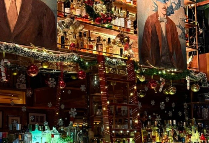 Polite & Co Hanoi bar interior. Shelves of liquor bottles, Christmas decorations, portraits. Gay travel destination for drinks.