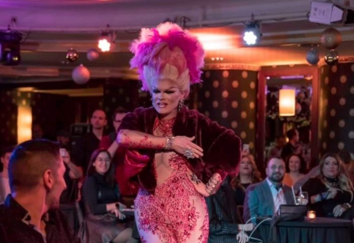 Drag queen performing at Polygon The Club Budapest. Gay nightlife travel destination. Pink feather headdress and sparkly red dress.