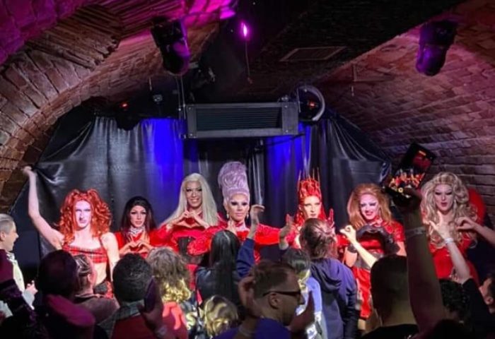 Drag queens perform at The Club Budapest, a gay bar. The audience enjoys the show in the venue's brick-arched setting. Nightlife.