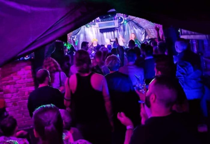 Inside Polygon The Club Budapest, a vibrant gay nightlife scene with people dancing and performers on stage under colorful lights.