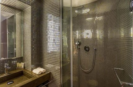 Bathroom at Hôtel Jules & Jim, a popular gay adult-only hotel in Paris. Features mosaic tiles, sink, and shower. Modern design.