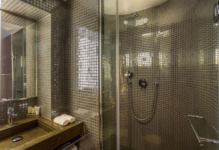 Bathroom at Hôtel Jules & Jim, a popular gay adult-only hotel in Paris. Features mosaic tiles, sink, and shower. Modern design.