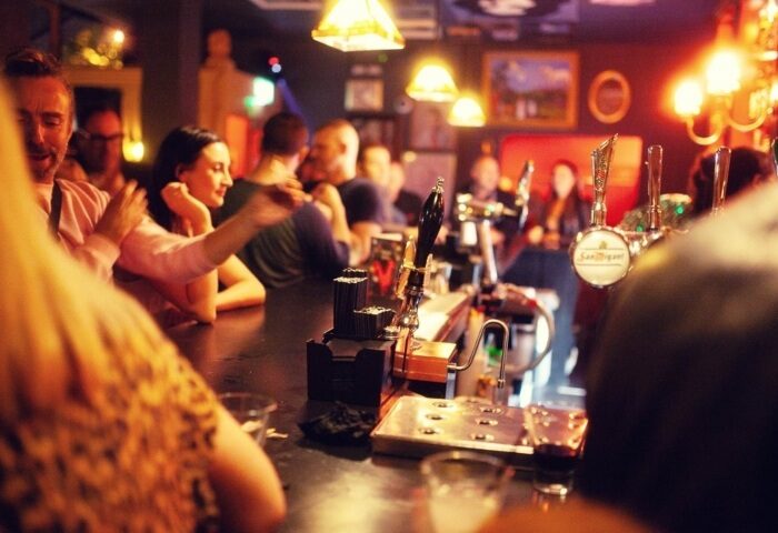 Interior view of The Cock Tavern, a popular gay bar in London. People are enjoying drinks at the bar.