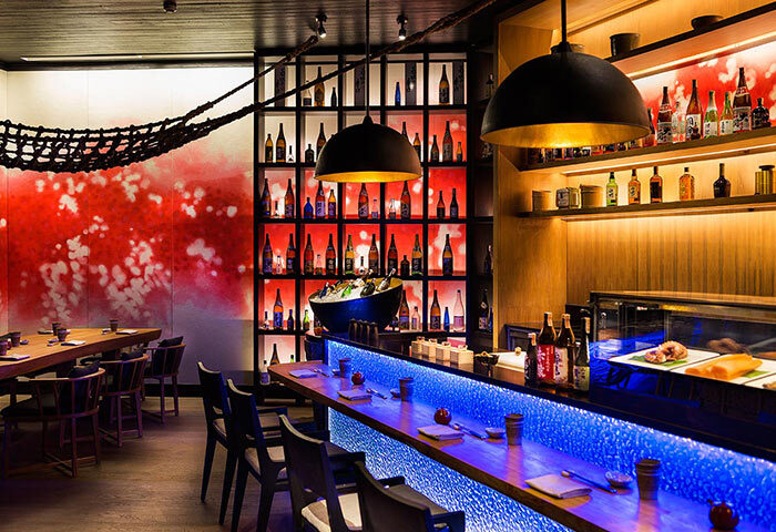 LUX* South Ari Atoll, Maldives gay beach hotel. Sushi bar interior with blue lighting, sake bottles, and modern design elements. Upscale dining.