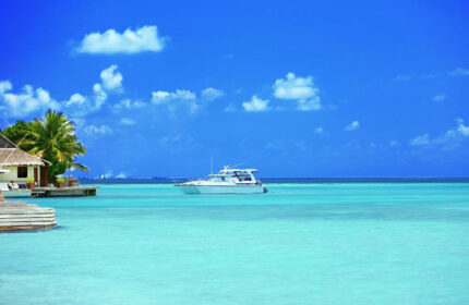 Malahini Kuda Bandos Resort, Maldives: Boat on turquoise water near a bungalow. Popular gay honeymoon hotel destination for gay men's travel.