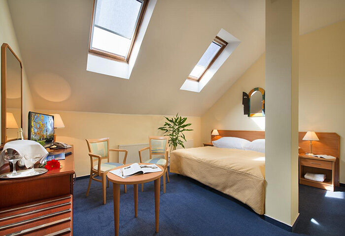 EA Hotel Tosca room in Prague's gayborhood Vinohrady. Cozy interior with skylights, bed, and seating. Popular gay hotels for travel.