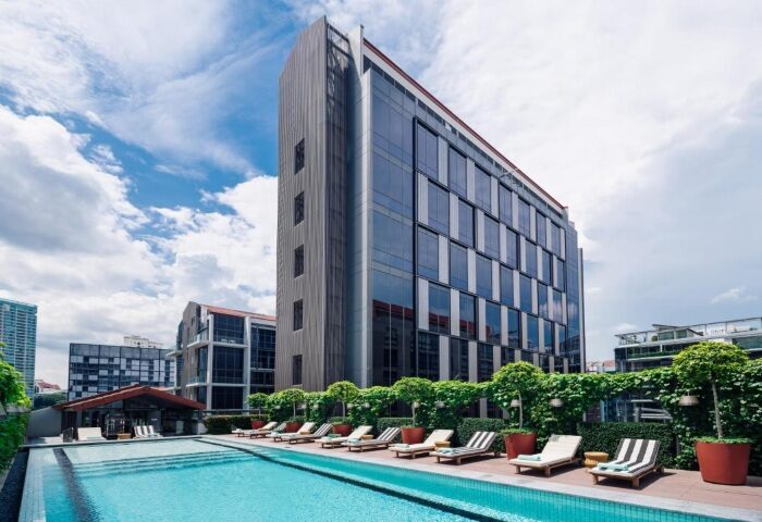 M Social Singapore hotel with outdoor swimming pool. Gay-friendly hotel in Singapore. Loungers by the pool. Modern architecture.