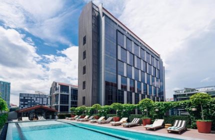 M Social Singapore hotel with outdoor swimming pool. Gay-friendly hotel in Singapore. Loungers by the pool. Modern architecture.